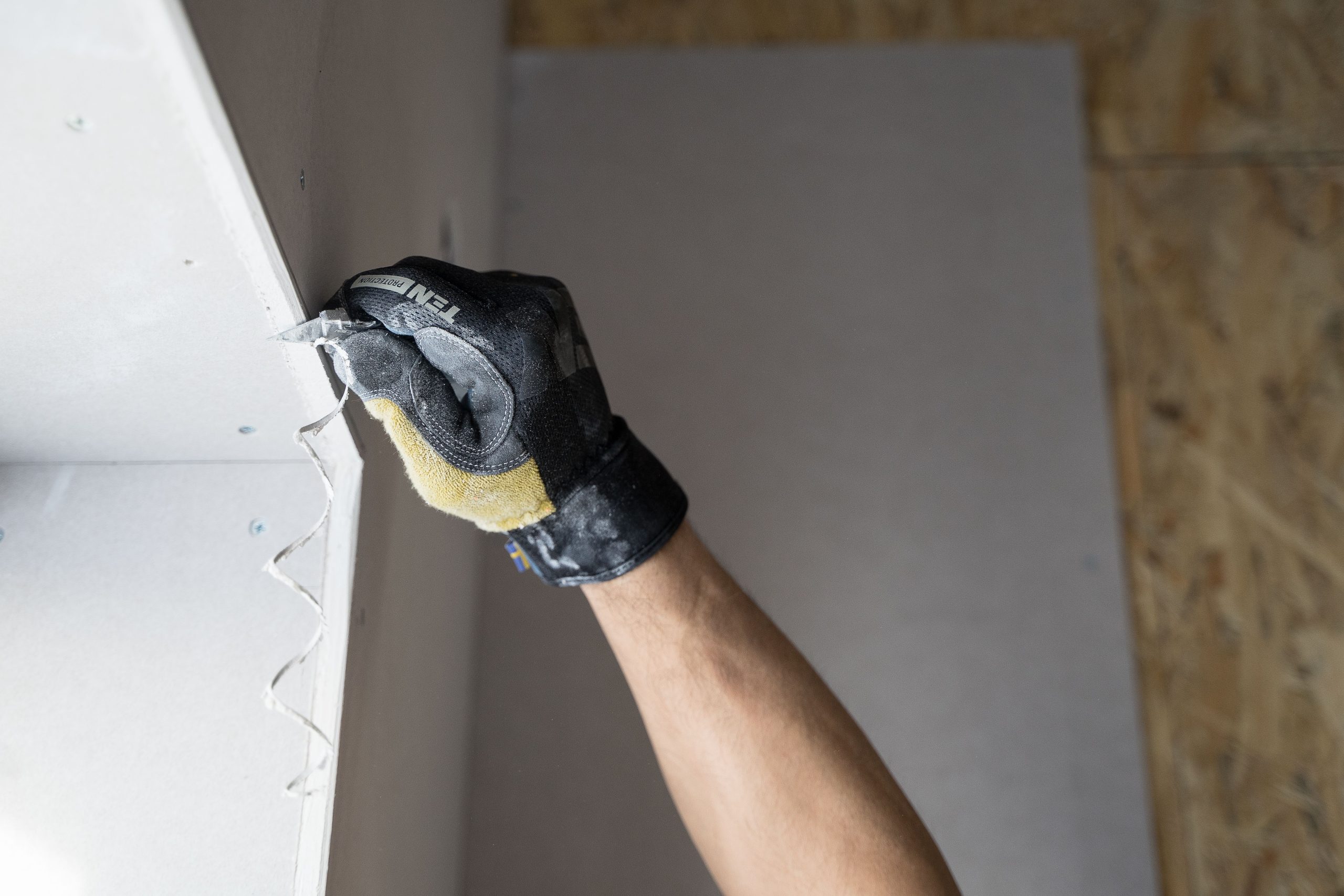 Main gantée étalant plâtre sur mur