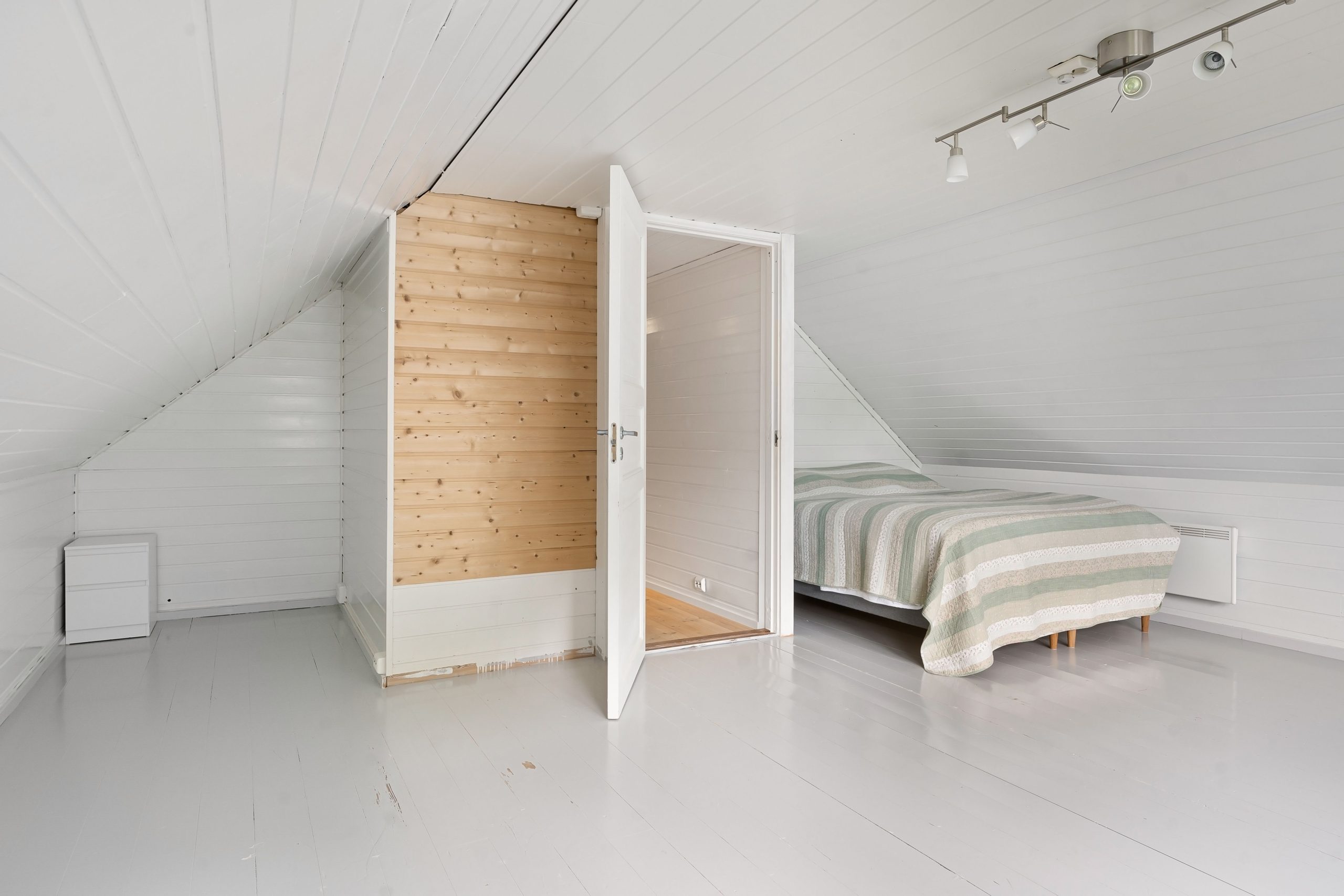 Chambre mansardée moderne aux murs blancs épurée