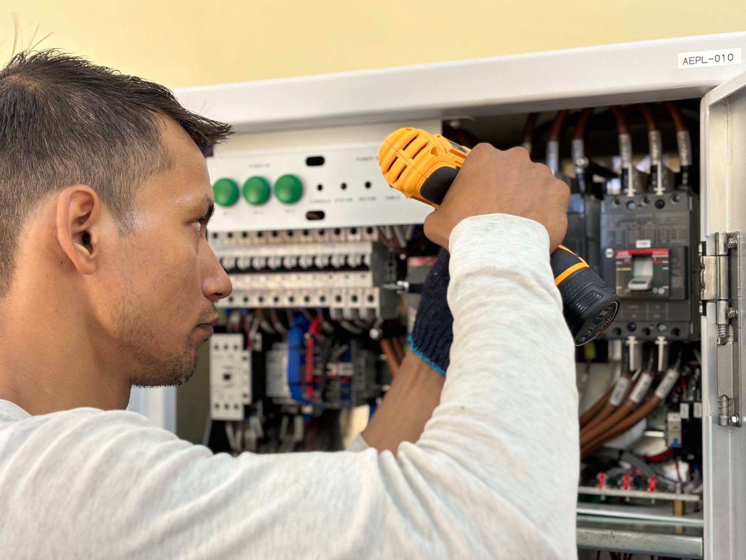 Électricien utilisant une perceuse sur un tableau électrique