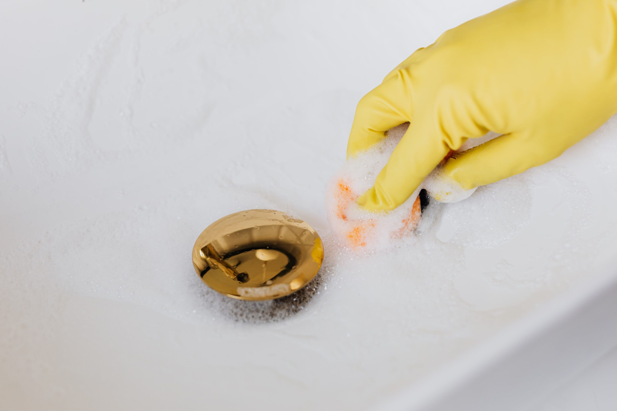Personne nettoyant un lavabo avec une éponge